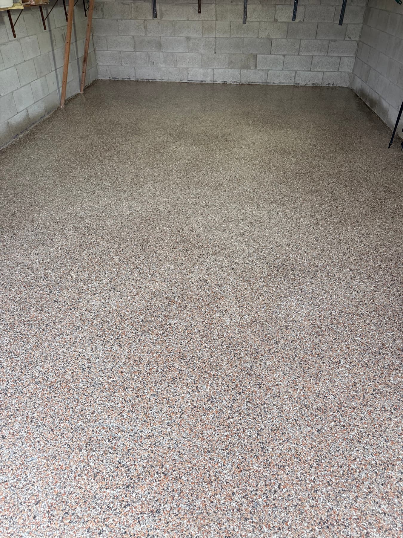 A finished beige and tan flake epoxy garage floor with a high-gloss sheen, wall to wall