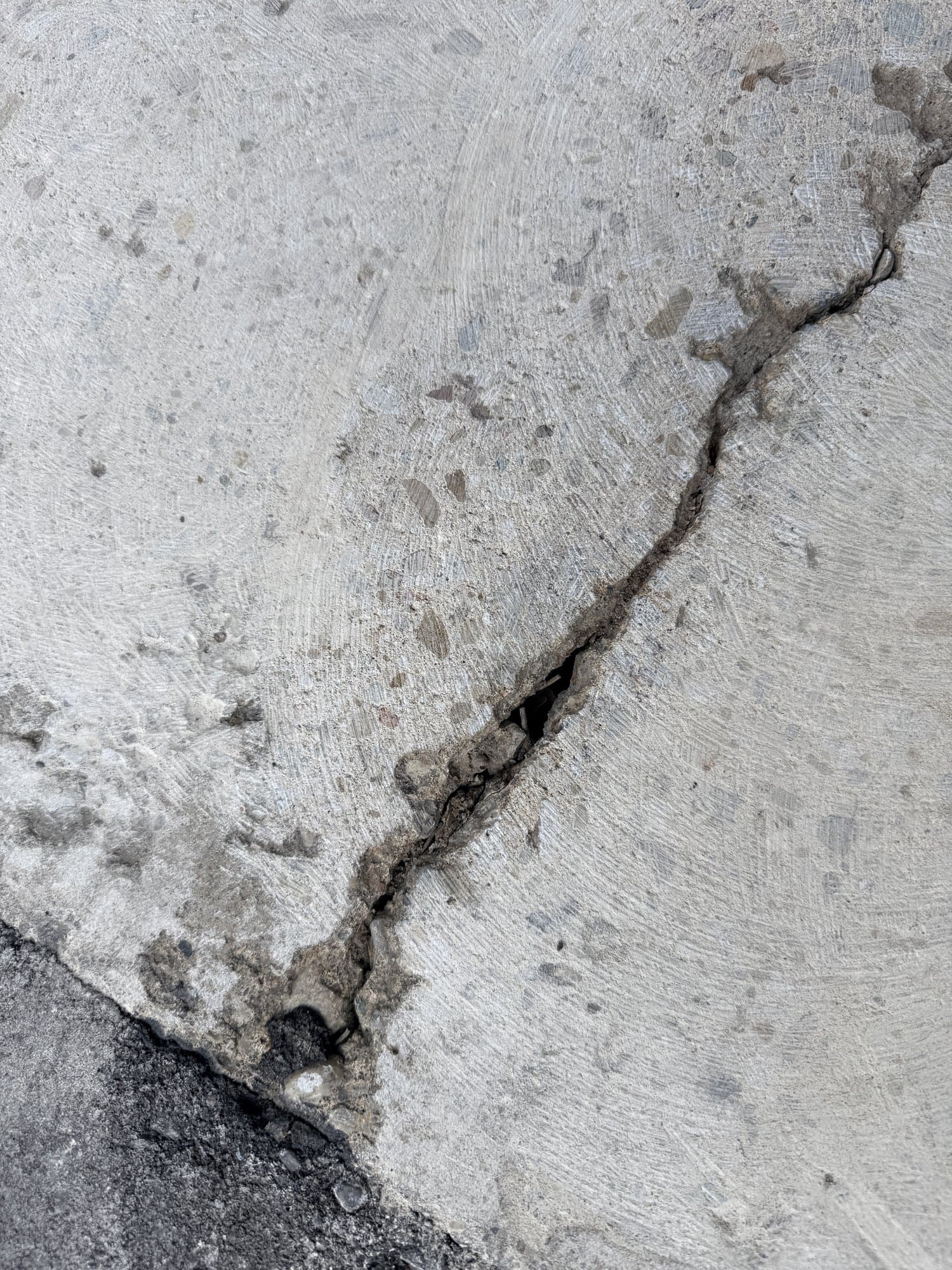 Close detail of the crack and failing concrete edge before repair