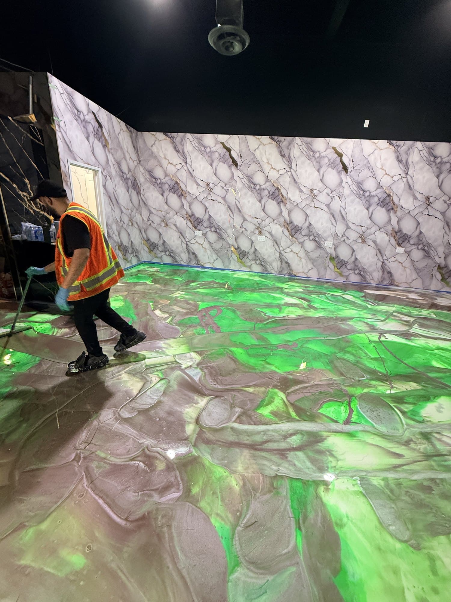 The finished green metallic floor seen across the full showroom with a person for scale