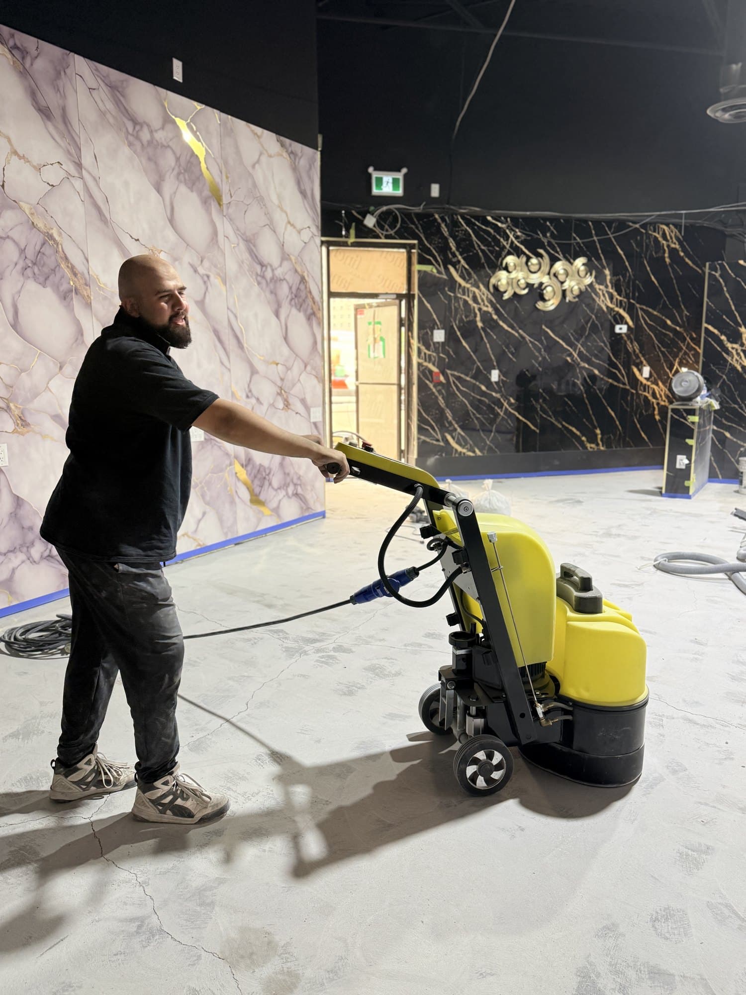 An installer diamond-grinding a commercial floor with a walk-behind grinder