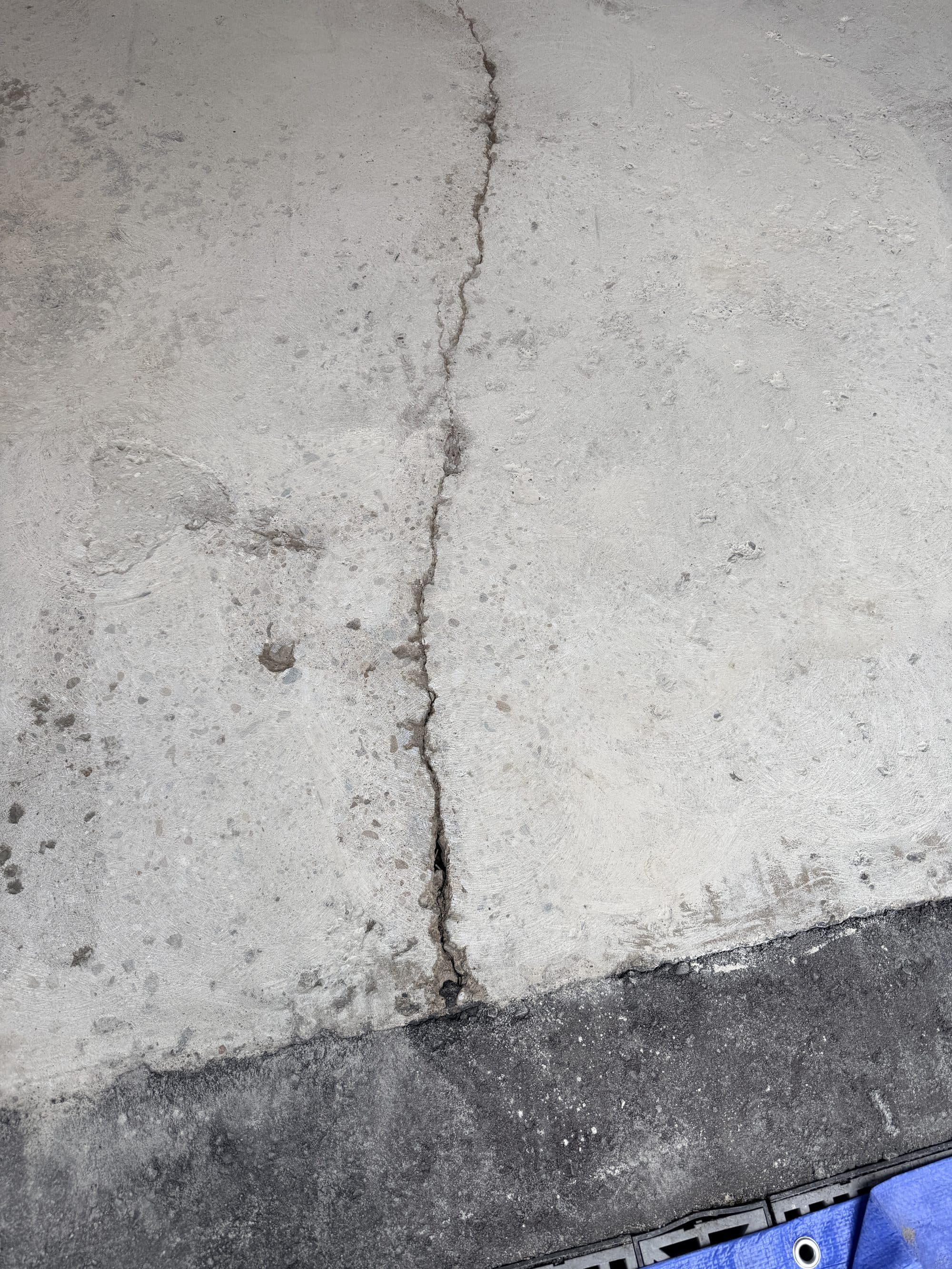 A crack running the length of a garage slab, photographed before grinding