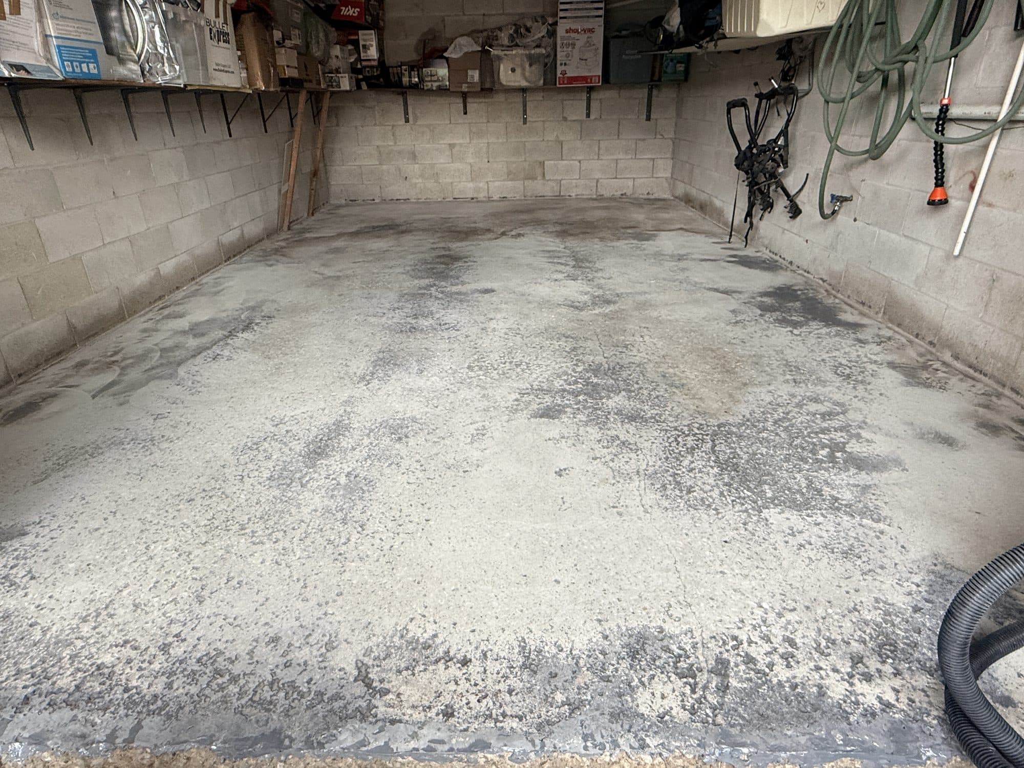 A bare garage slab stained with oil and tyre marks, before any LiquidLux coating
