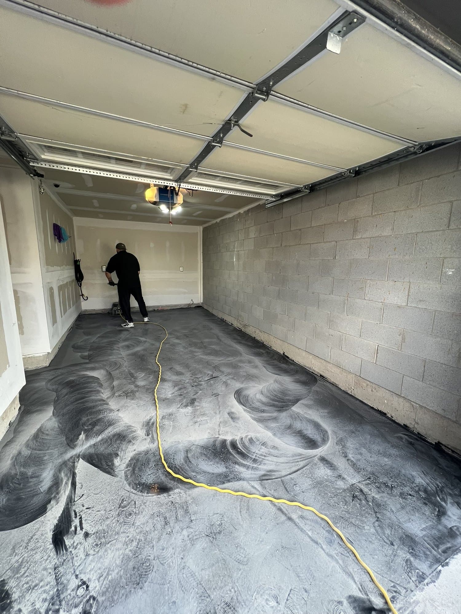A garage floor mid-pour, metallic epoxy spreading across the full slab