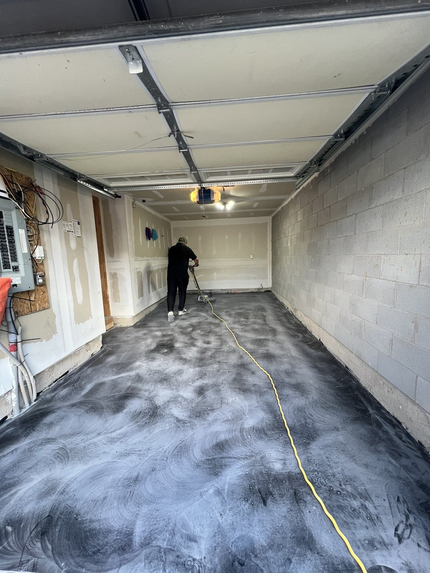 Silver and charcoal metallic epoxy being spread across a garage floor, marbling as it moves