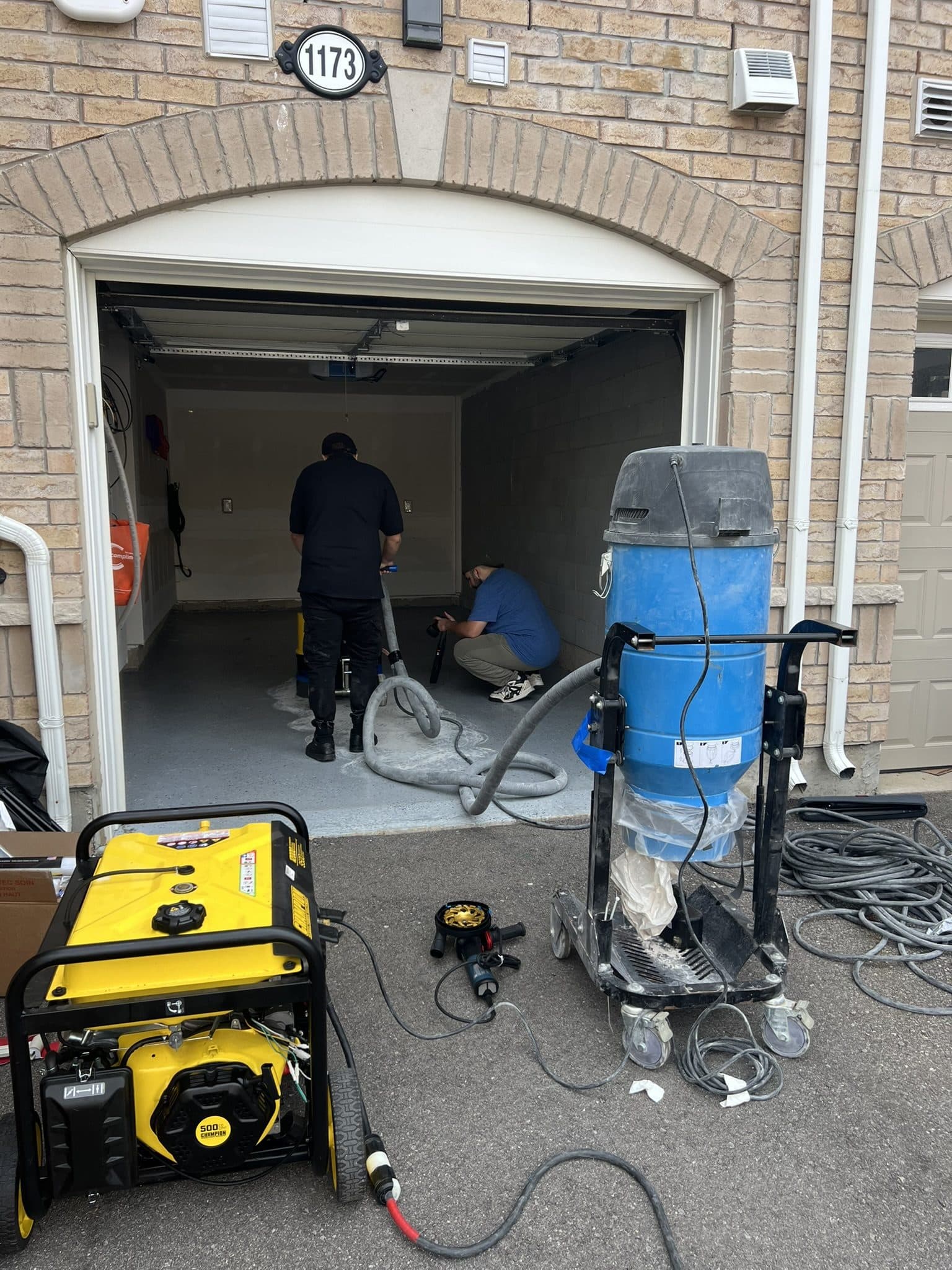 A floor grinder, industrial vacuum and generator staged in a driveway before an epoxy install